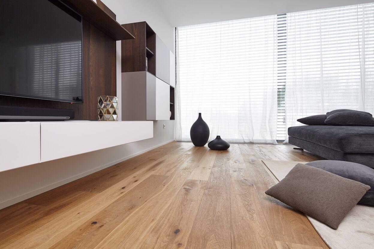 Modernes Wohnzimmer mit ma&szlig;gefertigten M&ouml;beln, Echtholzparkett und eleganter Wohnwand in Wei&szlig; und dunklem Holz.