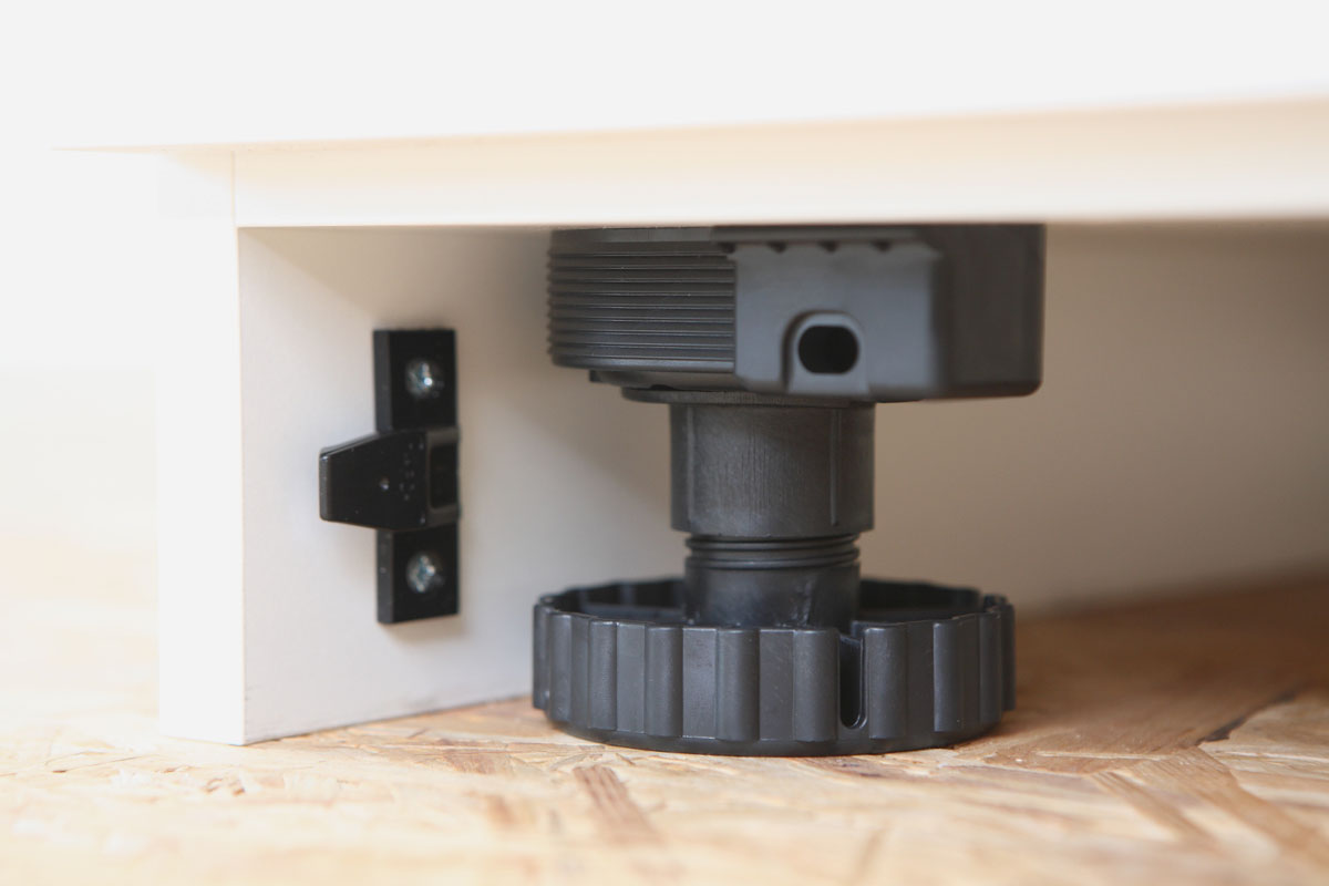 Detailaufnahme eines verstellbaren Sockels Detailaufnahme eines verstellbaren schwarzen Bodensockels mit Schraubmechanismus